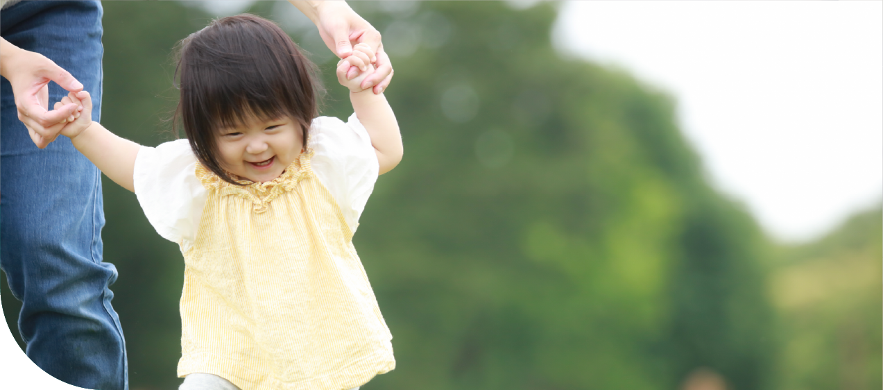 園児が大人の補助を受けながら歩いている姿