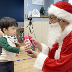 プレゼントを手渡すサンタと喜んでいる園児の姿